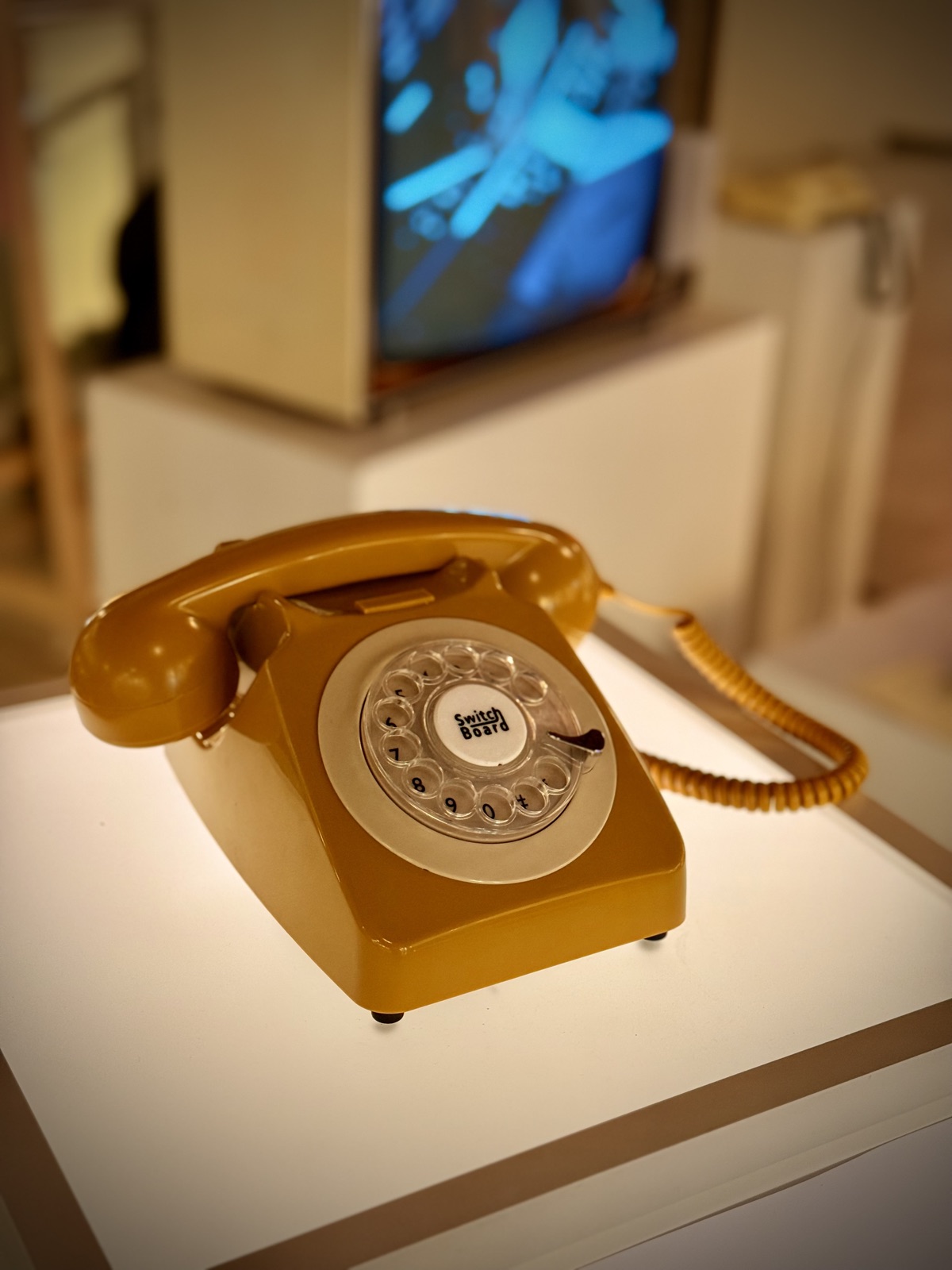 A vintage rotary phone on a white pedestal in the foyer of Parktheater Eindhoven, with a small CRT TV beside it.